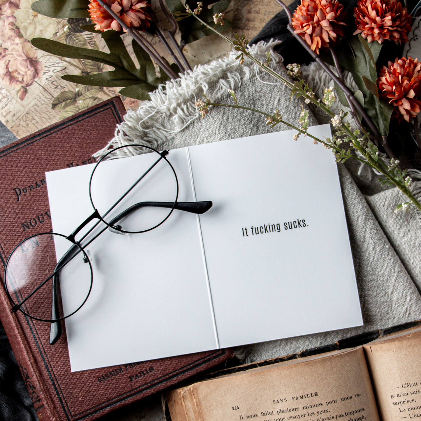 Open book with a printed phrase, glasses, and flowers on an old book