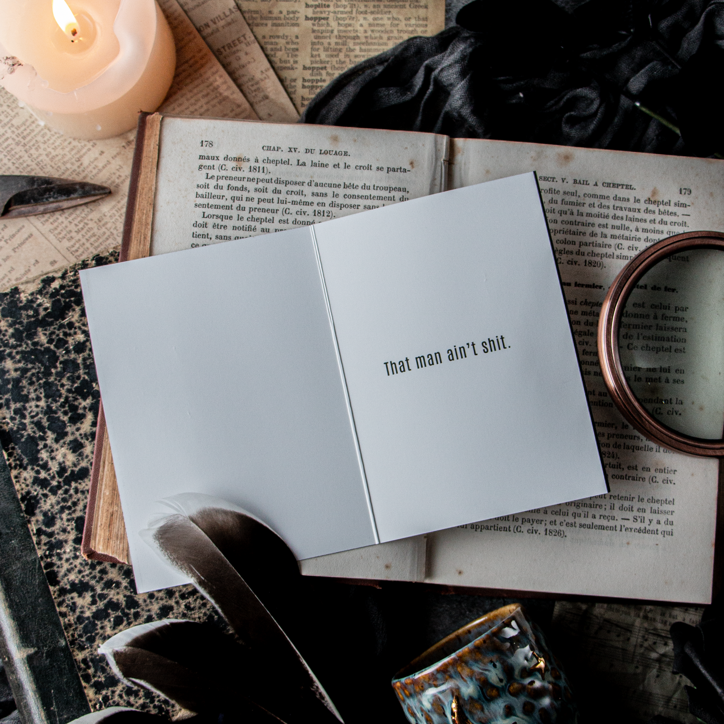 Open card with text on an open book with a candle and feather nearby.
