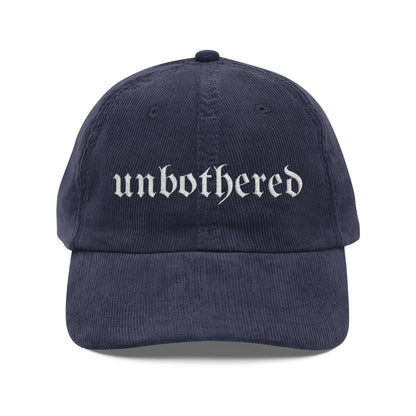 Navy blue cap with 'unbothered' text on a white background