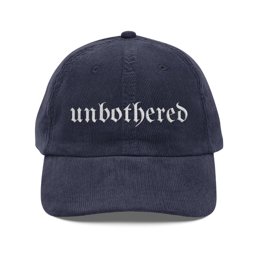 Navy blue cap with 'unbothered' text on a white background