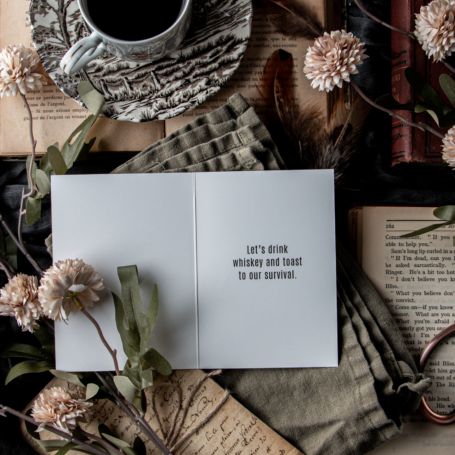 Cup of coffee, card, and books on a textured surface.