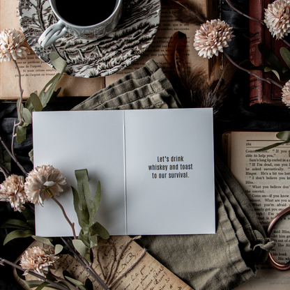 Cup of coffee, card, and books on a textured surface.
