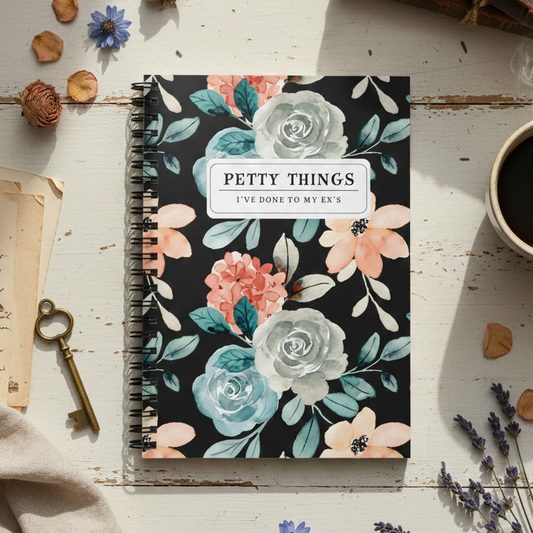 Notebook titled 'Petty Things' with floral design on a rustic wooden surface with coffee and flowers.