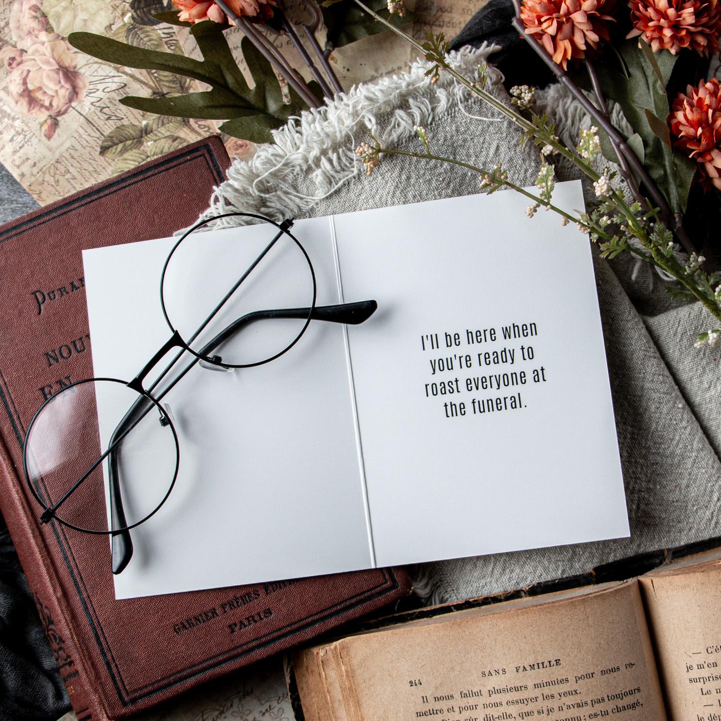 Open book with glasses on top, surrounded by flowers and books, with a humorous quote.