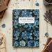 Notebook with blue floral design on a wooden surface with books and lavender.