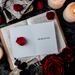 A greeting card with a bold statement placed inside an open book, surrounded by rose petals and candles, depicting a theme of freedom or separation.
