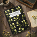 Notebook with floral design on a wooden surface with coffee and flowers