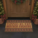 Doormat with offensive text in front of a wooden door decorated for Christmas.